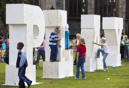 kids playing on big letters spelling play